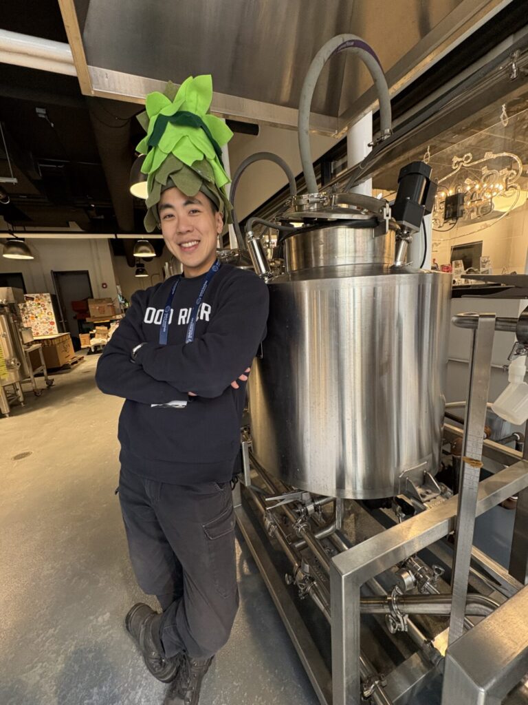 Asher Sun posing in a brewhouse wearing his custom made Hop Hat